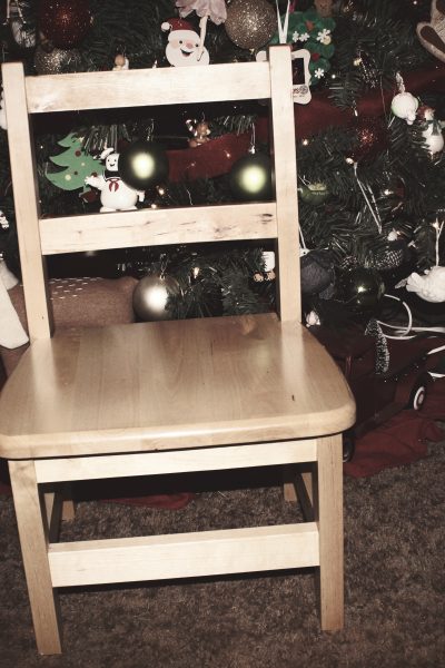 An empty chair in front of Christmas Tree