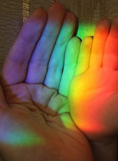 picture of the hand of a child and mother with a rainbow on the background of wallpaper
